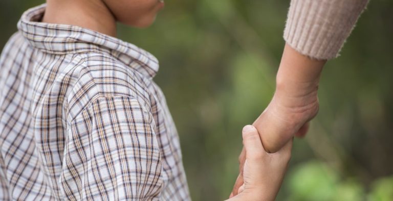 Father asks court to terminate mother’s parental rights so he and his wife can adopt child A father holding a young child’s hand, symbolising parental care and adoption.
