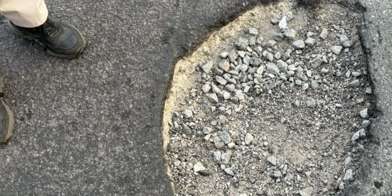 Motorcyclist chose the safest route through potholes on a damaged road, but still crashed Potholes and damaged sections of a road creating hazards for motorists